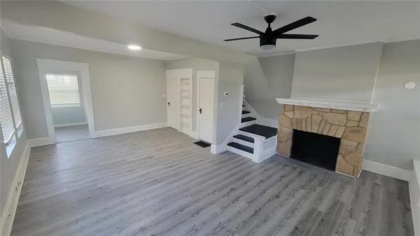 an empty room with wooden floor a fireplace and windows