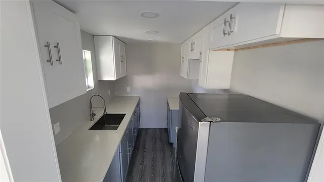a kitchen with a sink a refrigerator and cabinets