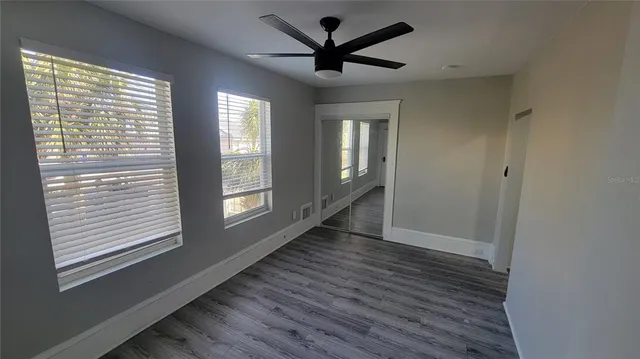 a view of empty room with wooden floor and fan