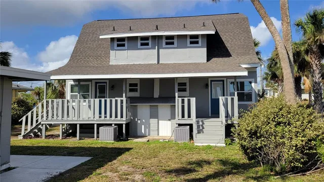 a view of a white house with large windows and plants