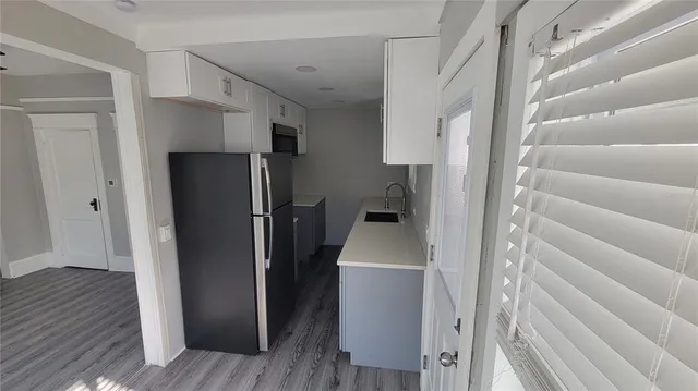 a view of a kitchen with refrigerator and wooden floor