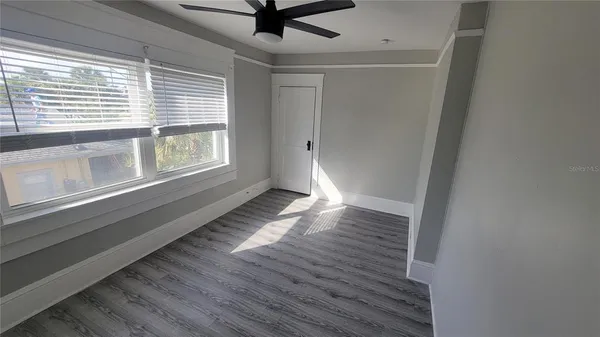a view of an empty room with wooden floor and a window