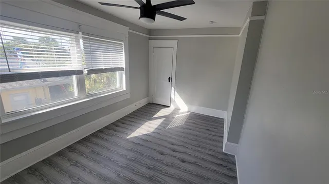 a view of an empty room with wooden floor and a window