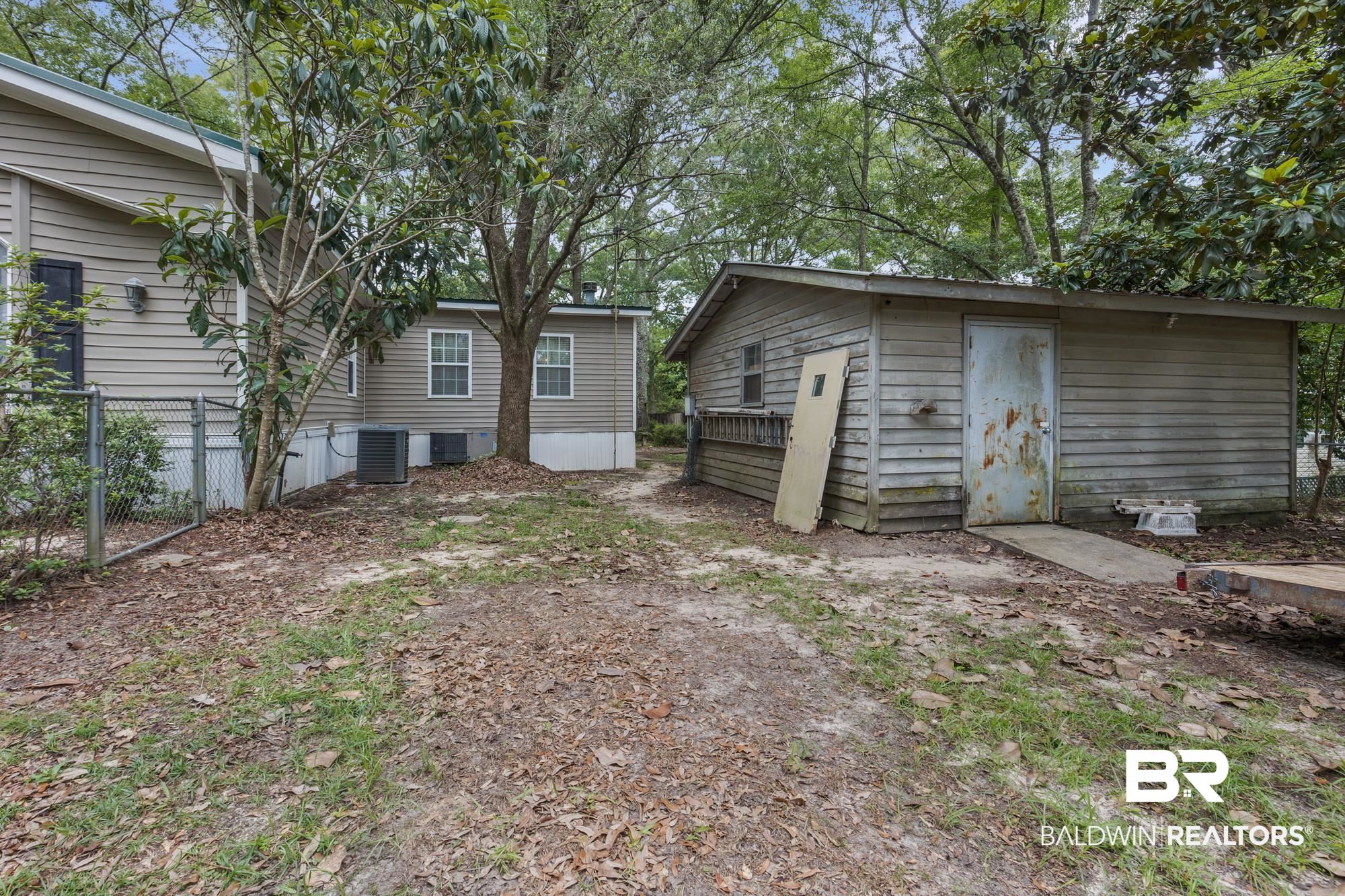 8675 Hunters Pointe Drive North Theodore, AL 36582 - Photo 19 of 20 Wood-sided outbuilding with a metal entry door and concrete pad