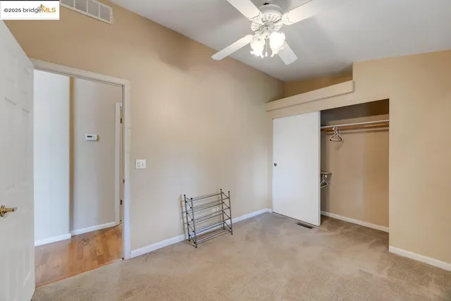 a view of an empty room with a chandelier fan