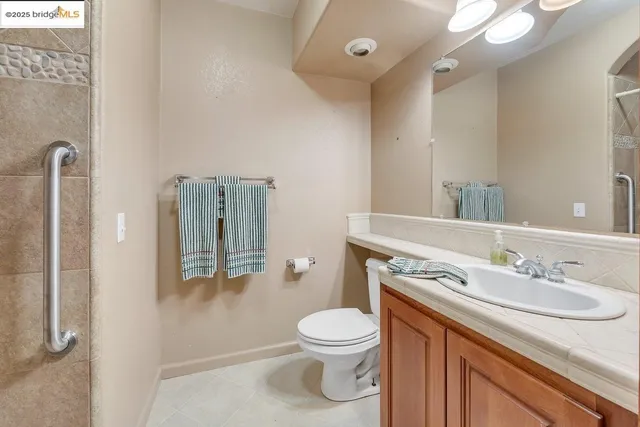 a bathroom with a granite countertop sink a toilet and a mirror