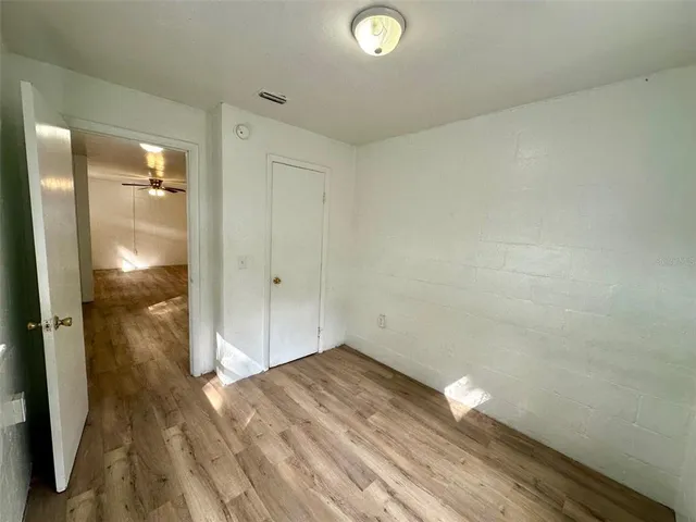 an empty room with wooden floor and closet area