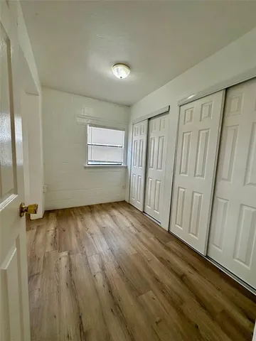 an empty room with wooden floor and fan
