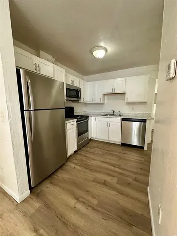 a kitchen with a sink a refrigerator a microwave and cabinets