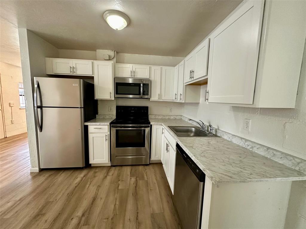 647 Northeast Waldo Road Gainesville, FL 32641 - Photo 10 of 25 a kitchen with a sink a refrigerator a microwave and cabinets