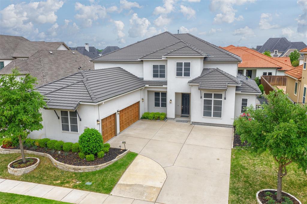 918 Sydney Lane Allen, TX 75013 - Photo 2 of 40 The property features a white exterior with a dark tiled roof, a paved driveway, and a two-car garage with wooden doors