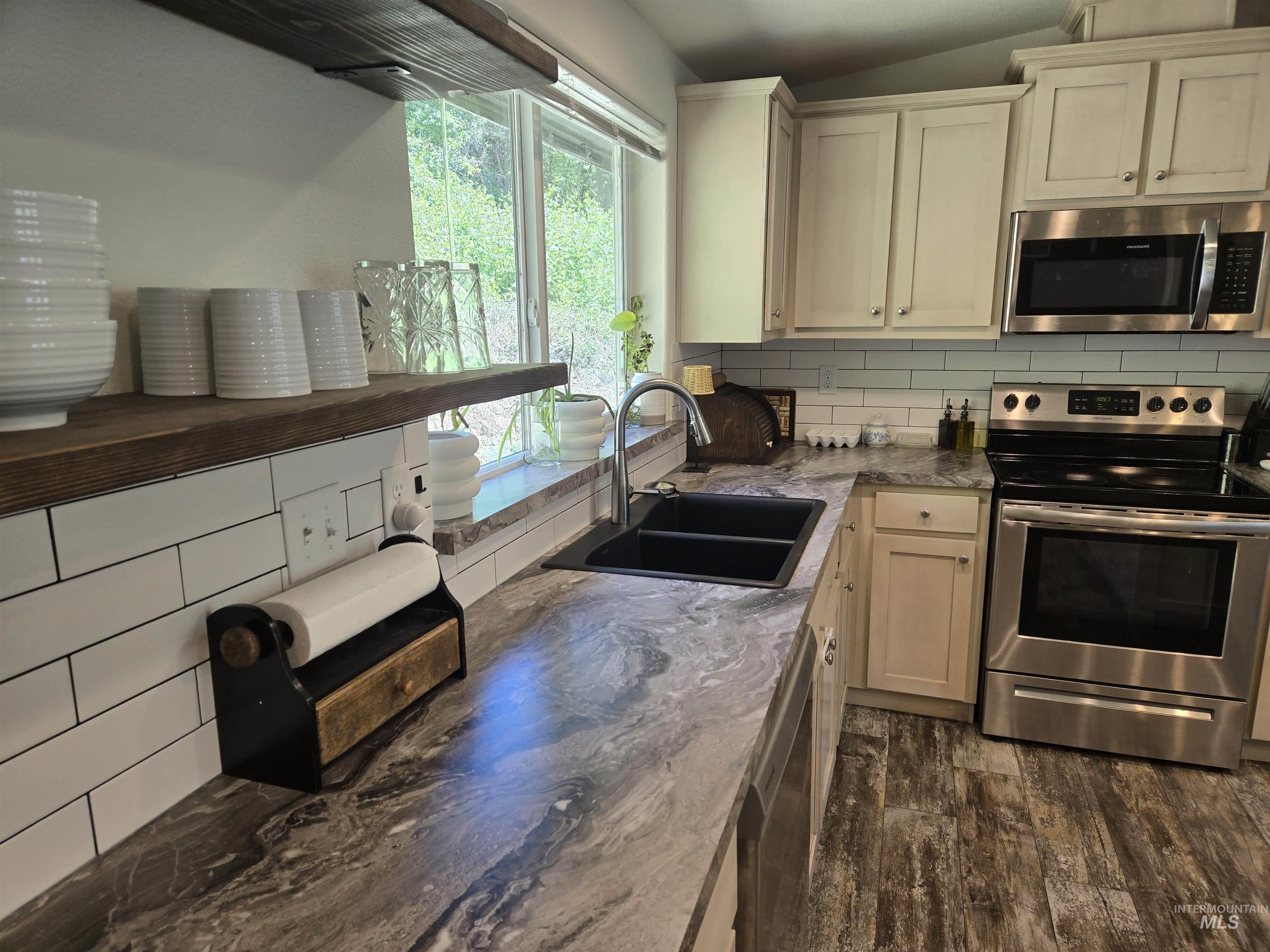 174 Konkolville Road Orofino, ID 83544 - Photo 9 of 43 Kitchen featuring white subway tile backsplash, dark wood-finish open shelving, stainless steel appliances, a double basin sink, and wood-finish flooring