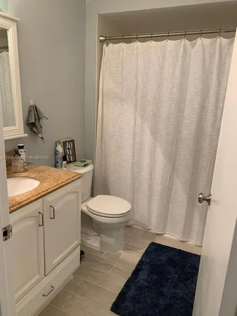 a bathroom with a sink a toilet a shower curtain and a mirror