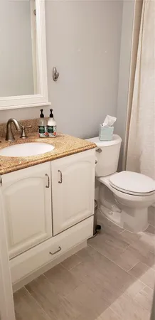 a bathroom with a granite countertop toilet sink and mirror