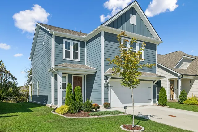 a front view of a house with a yard and trees
