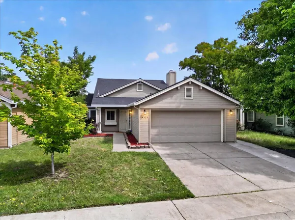 a view of a house with a yard and large tree