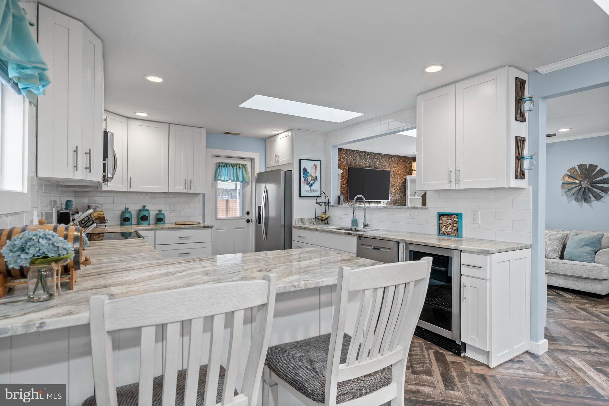 317 Biddle Road Accokeek, MD 20607 - Photo 14 of 44 a kitchen with stainless steel appliances kitchen island granite countertop a stove a refrigerator a sink a dining table and chairs with wooden floor
