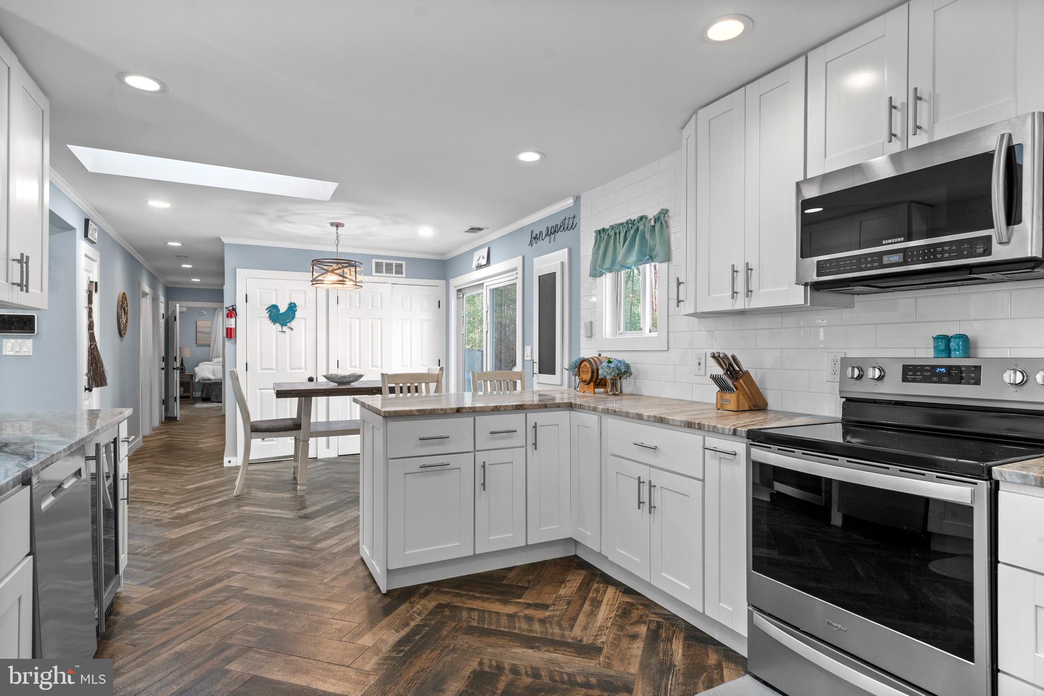 317 Biddle Road Accokeek, MD 20607 - Photo 15 of 44 a kitchen with stainless steel appliances granite countertop a stove top oven a sink dishwasher a dining table and chairs with wooden floor