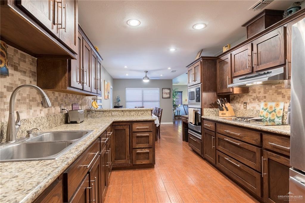 2801 Hawk Avenue McAllen, TX 78504 - Photo 7 of 19 a kitchen with stainless steel appliances granite countertop sink stove top oven and cabinets