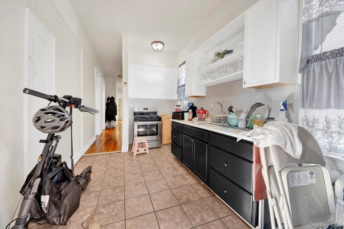 2312 Morgan Avenue Bronx, NY 10469 - Photo 14 of 36 Kitchen with dark cabinetry, open shelves, stainless steel range with gas stovetop, white cabinetry, and light countertops