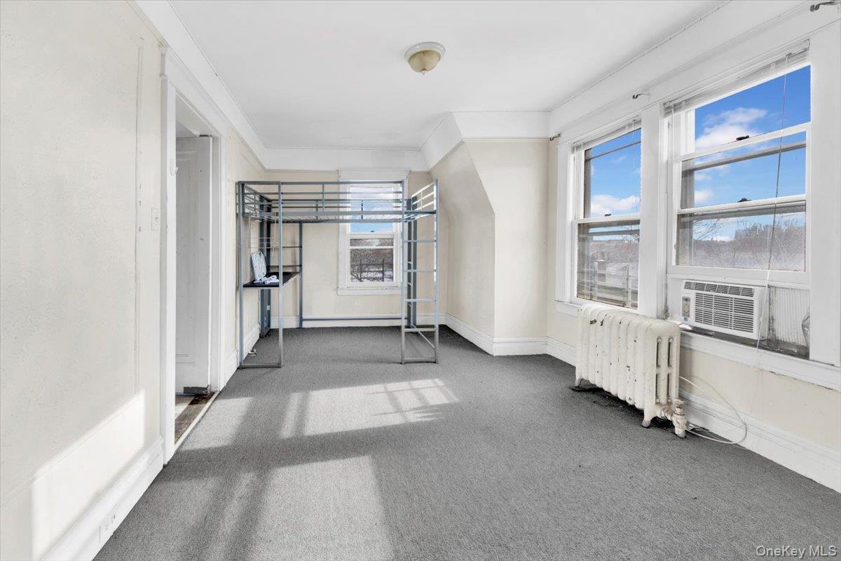 2312 Morgan Avenue Bronx, NY 10469 - Photo 21 of 36 Unfurnished bedroom with radiator, multiple windows, light carpet, and cooling unit