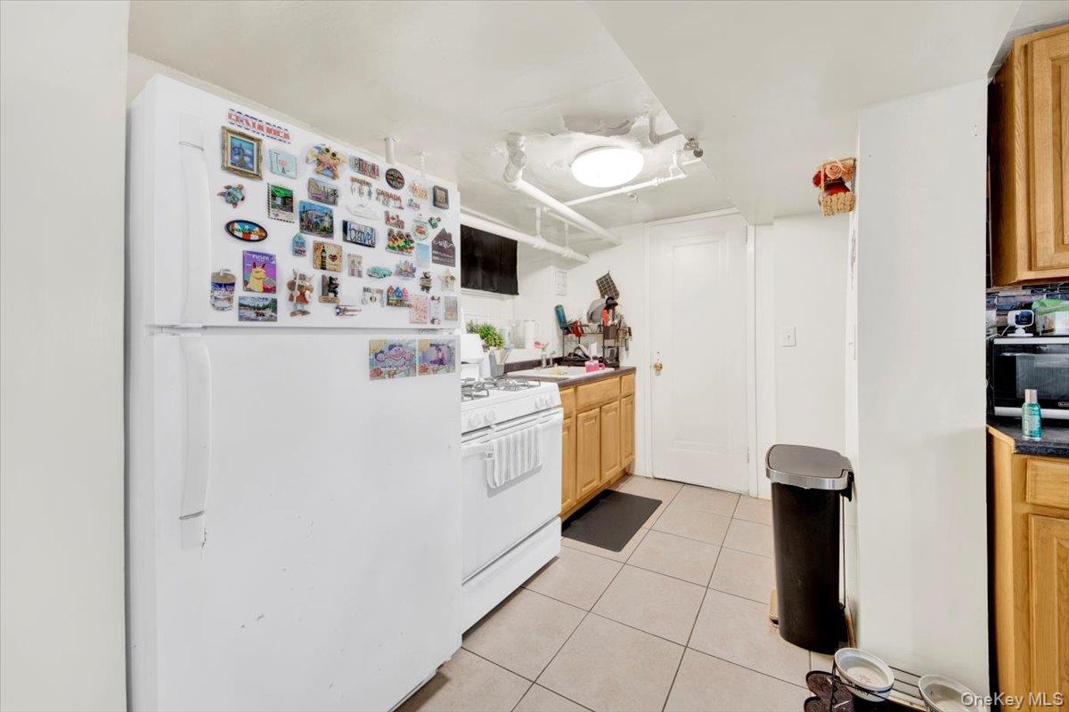 2312 Morgan Avenue Bronx, NY 10469 - Photo 31 of 36 Kitchen with white appliances, light tile patterned floors, dark countertops, and light brown cabinetry