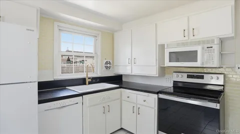 a kitchen with granite countertop white cabinets and black appliances