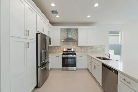 a kitchen with stainless steel appliances granite countertop a stove a refrigerator and a sink
