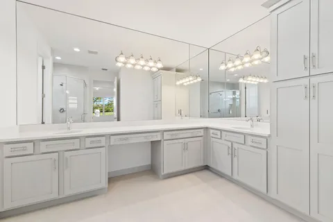 a large white kitchen with a lot of white cabinets and chandelier