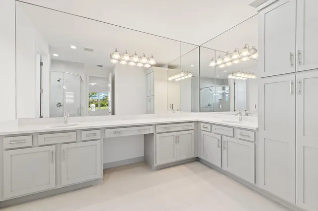 a large white kitchen with a lot of white cabinets and chandelier