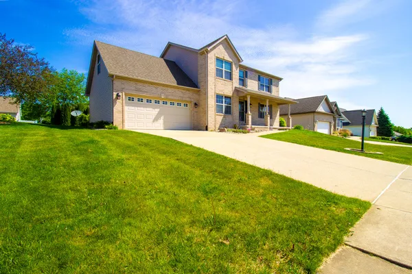 a view of a big house with a big yard and large trees