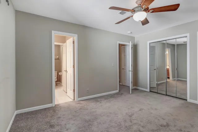 an empty room with closet and a ceiling fan