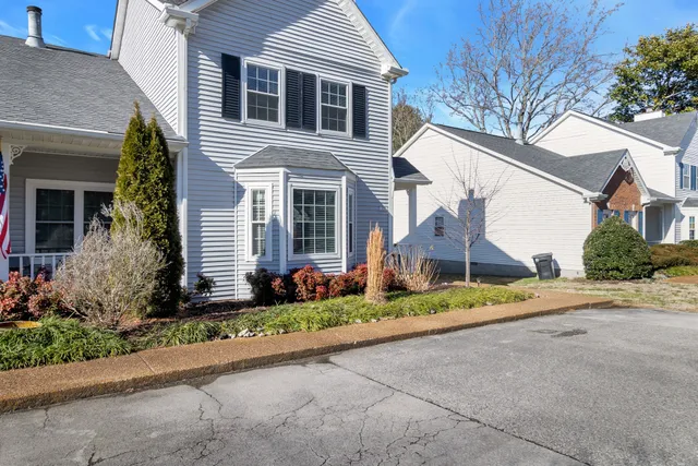 a view of a white house with a small yard and palm trees
