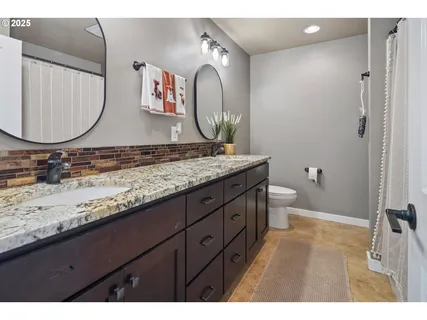a bathroom with a granite countertop toilet sink and mirror