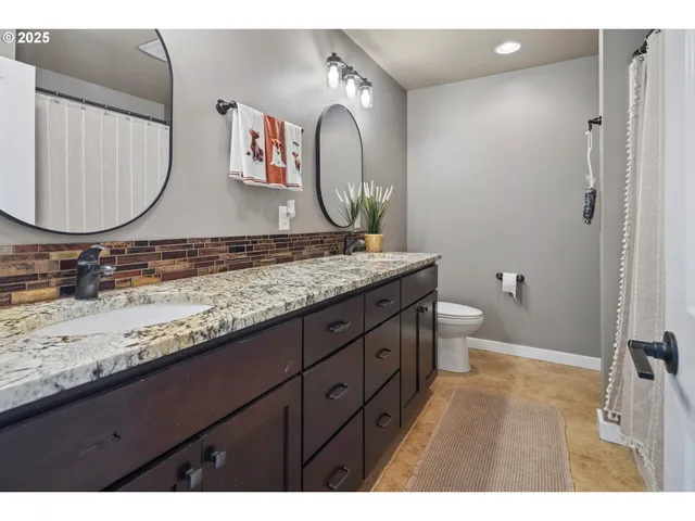 a bathroom with a granite countertop toilet sink and mirror
