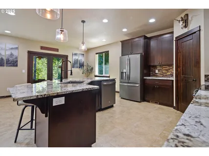 a kitchen with granite countertop a table chairs stainless steel appliances and cabinets