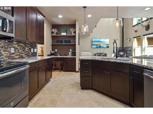 a kitchen with stainless steel appliances granite countertop wooden cabinets a sink dishwasher a stove and a refrigerator