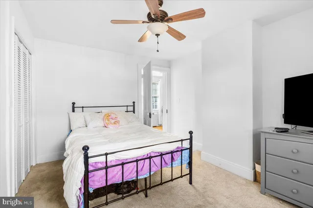 a bedroom with a bed a chandelier and a flat tv screen on a dresser