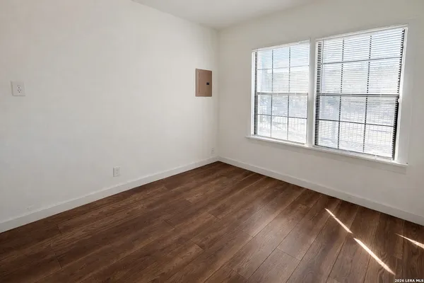 an empty room with wooden floor and windows