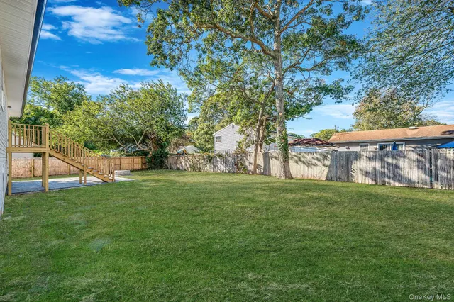 a view of a white house with a big yard and large trees