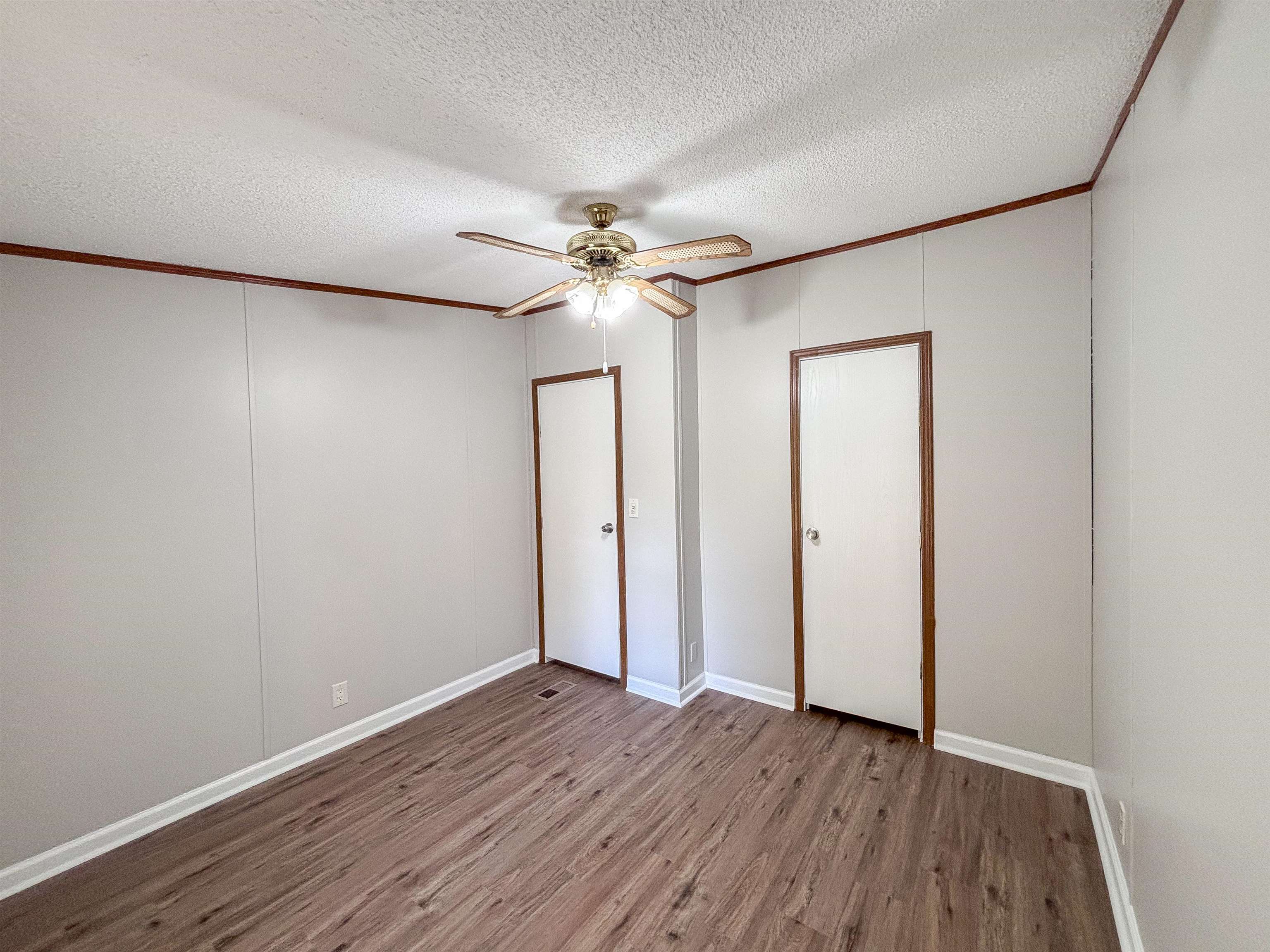 2847 Holly Grove Road Covington, TN 38019 - Photo 27 of 36 Spacious room featuring wood-finish flooring, light grey paneling, white baseboards, and two paneled doors with wood trim