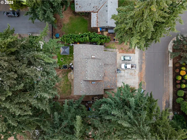 an aerial view of a house with a yard and trees all around