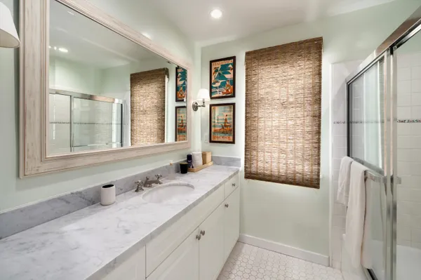 a bathroom with a granite countertop sink a mirror and a shower
