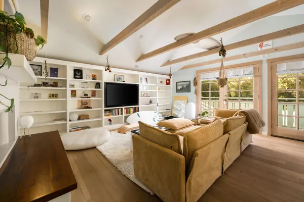 a living room with furniture a flat screen tv and floor to ceiling window