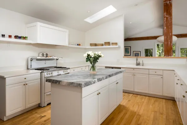 a kitchen with a sink dishwasher and white cabinets with wooden floor