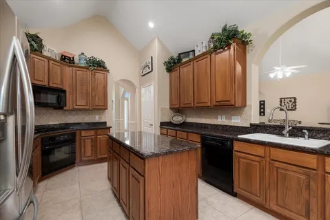 a kitchen with kitchen island granite countertop a sink stove and refrigerator