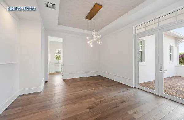 a view of an empty room with wooden floor and a ceiling fan