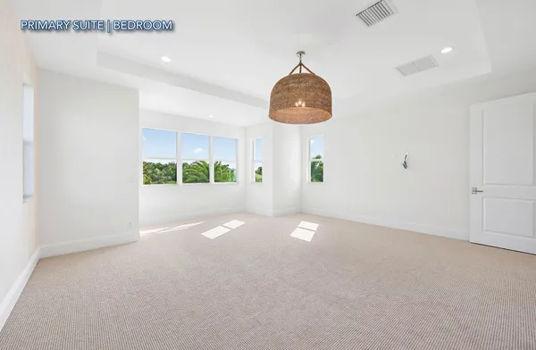 a view of an empty room with a chandelier fan and window