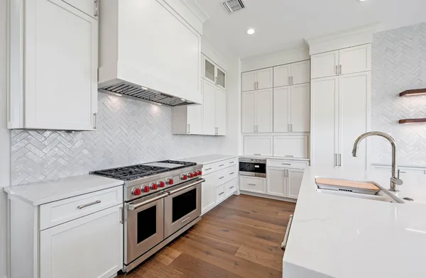 a kitchen with stainless steel appliances granite countertop a stove a sink and a white refrigerator with white countertops