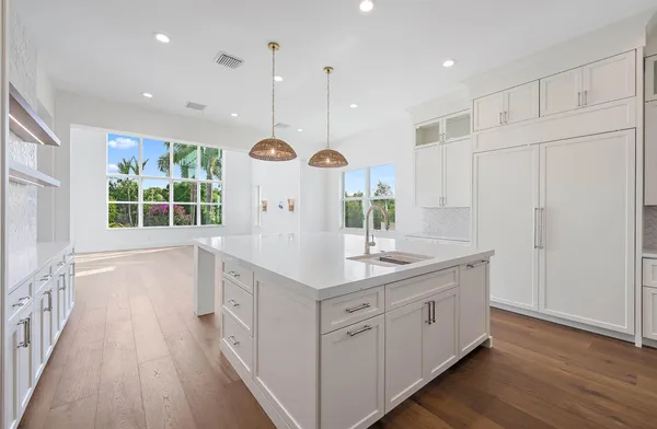 an open kitchen with a sink a window and wooden floors